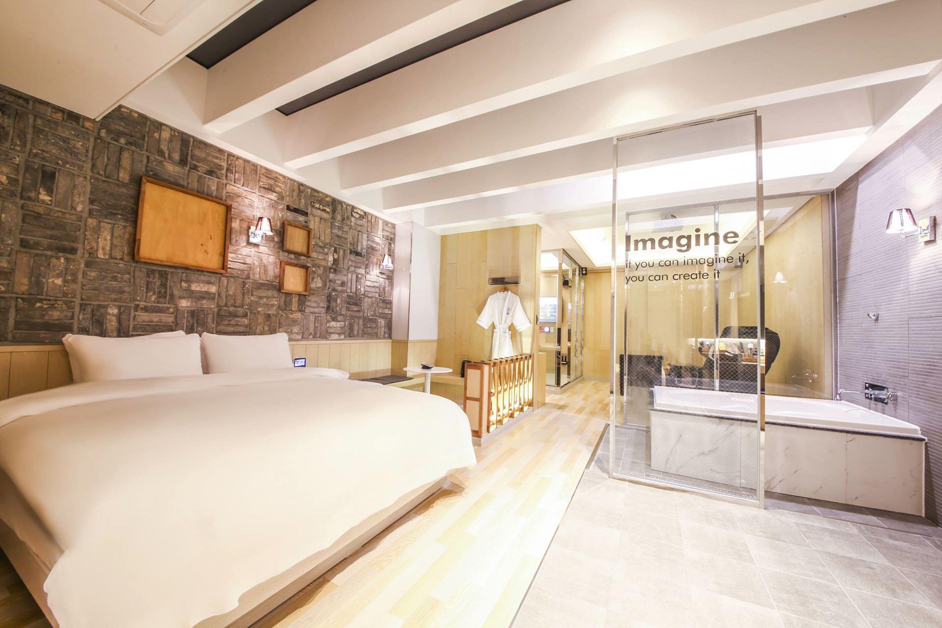 Een moderne hotelkamer met een groot bed, een douchecabine van glas en een muur met ingelijste foto's.