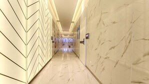 A corridor with a herringbone patterned wall and marble flooring, leading to a door with a sign. - HOTEL OSCAR (Daegu)