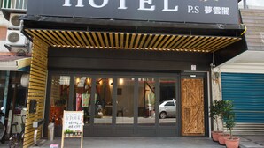 A hotel entrance with a large sign reading "HOTEL" and "P.S." in English and another language. There are potted plants outside, a bicycle, and a car parked in front. - PS Hotel (Jiaoxi)
