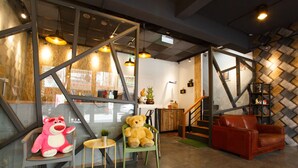 A cozy interior with a wooden staircase, a green chair, a red leather couch, and a teddy bear. - PS Hotel (Jiaoxi)