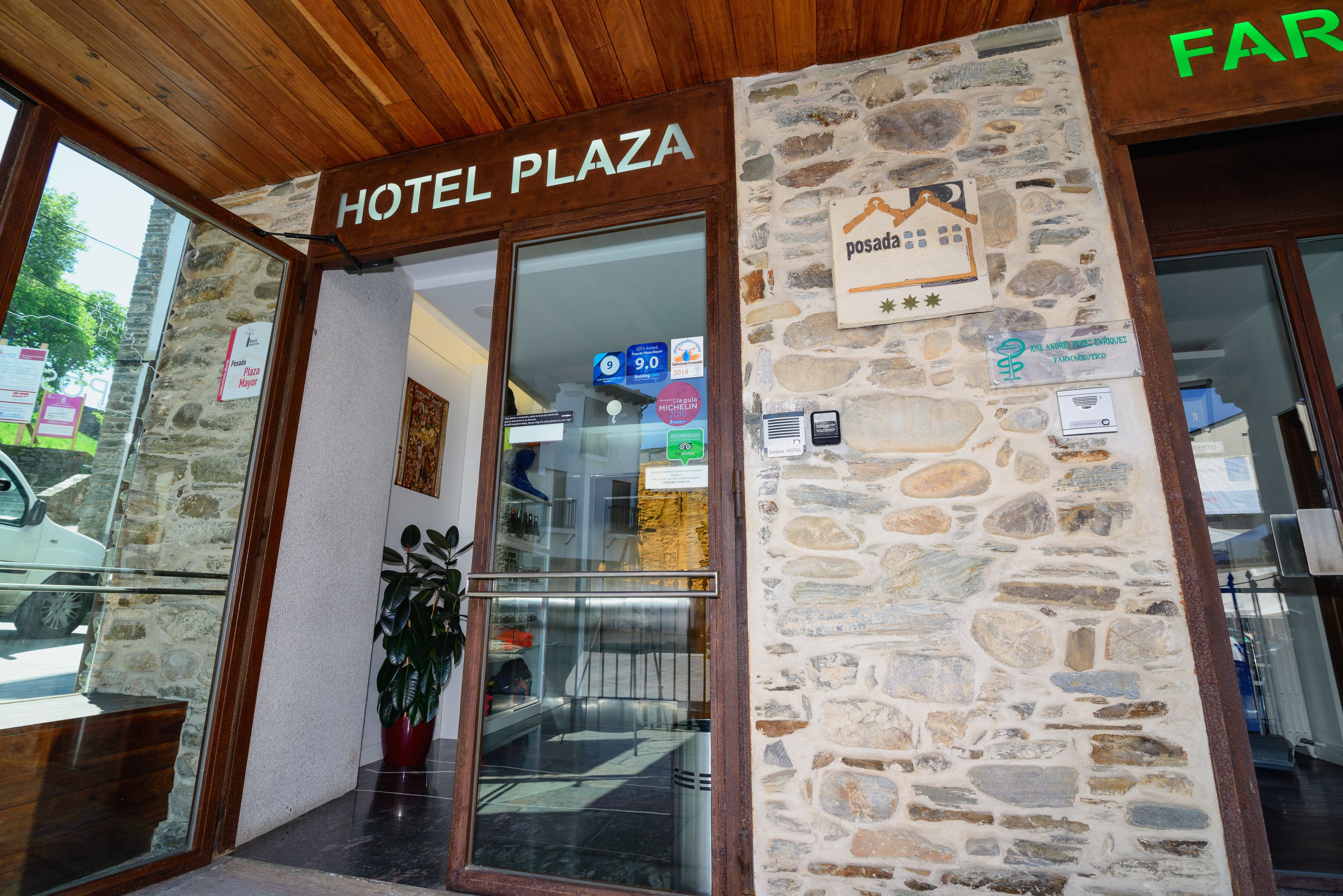 Entrada do Hotel Plaza, com fachada de pedra, teto de madeira e porta de vidro.
