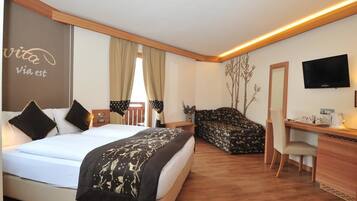 Habitación de hotel con cama, escritorio, silla, televisor y una pared con un letrero.