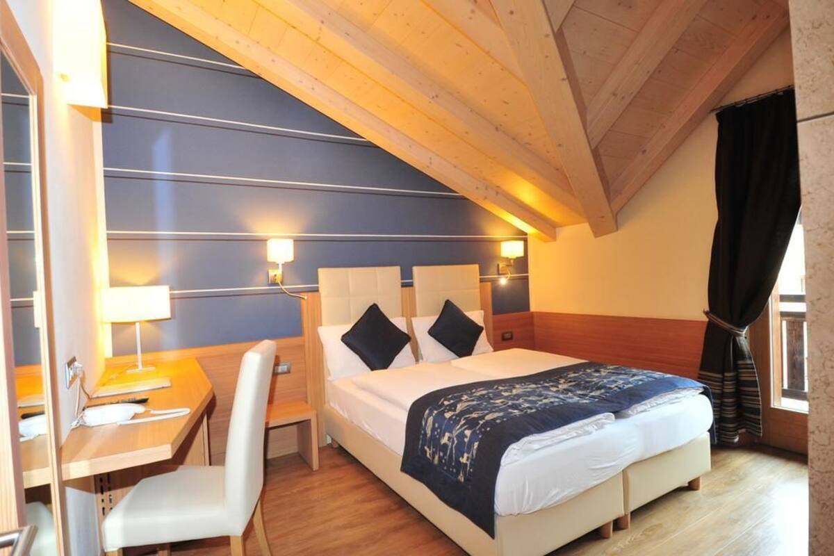 A bedroom with a bed, bedside tables, a desk, and a chair.