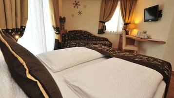 Une chambre d’hôtel avec un lit, un bureau, une télévision et une fenêtre avec des rideaux.