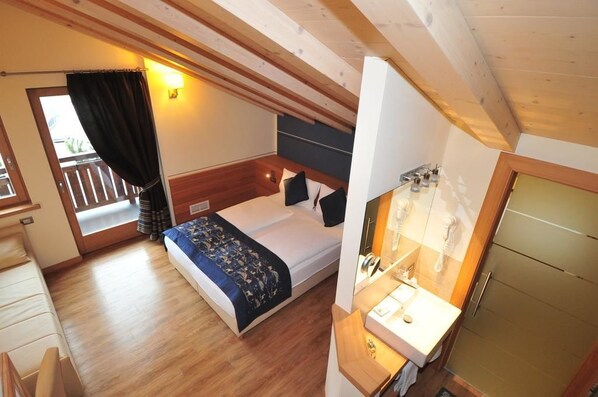 A bedroom with a bed, a bedside table, a mirror, and a window with curtains.
