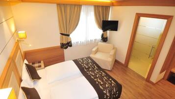 A hotel room with a bed, a chair, a television, and a wardrobe.