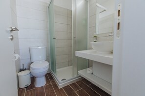 A modern bathroom with a toilet, a glass-enclosed shower, and a white sink.
