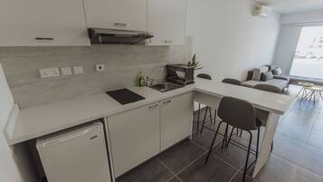 Una cocina moderna con armarios blancos, lavavajillas integrado y una zona de comedor con mesa y sillas.