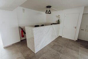 A modern kitchen with a marble countertop, a pendant light, and a fire extinguisher.