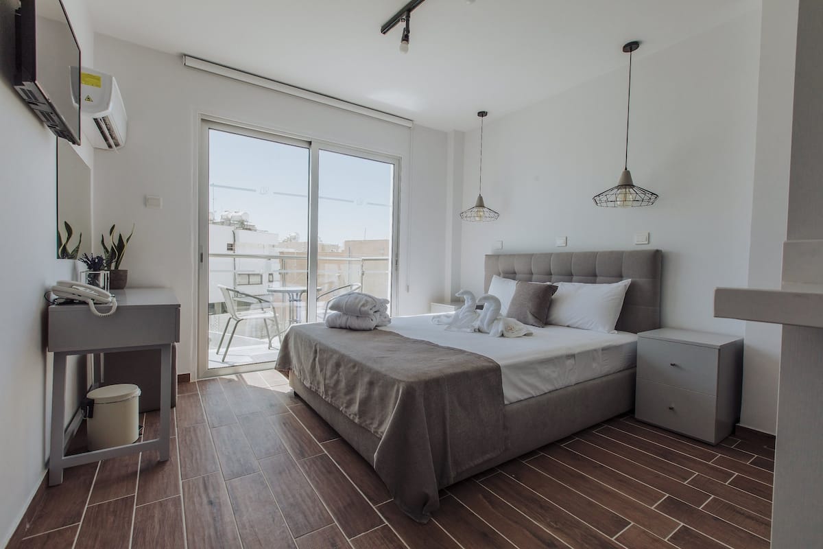 Un dormitorio moderno con una cama grande, mesitas de noche, un escritorio y un ventanal corredero que da a un balcón.