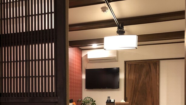A modern living room with a sofa, a dining table, and a TV mounted on the wall. - Kyoto Machiya UZUKI (Kyoto)