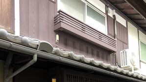 A traditional Japanese building with a dark wooden exterior, a tiled roof, and a sliding door with a grid pattern. - Kyoto Machiya UZUKI (Kyoto)