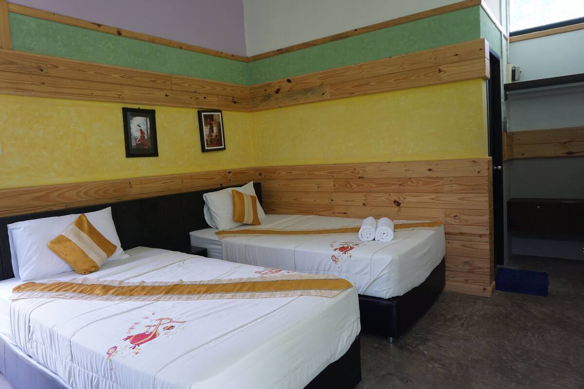 Una habitación de hotel con dos camas, cabeceros de madera y una pared verde y amarilla.