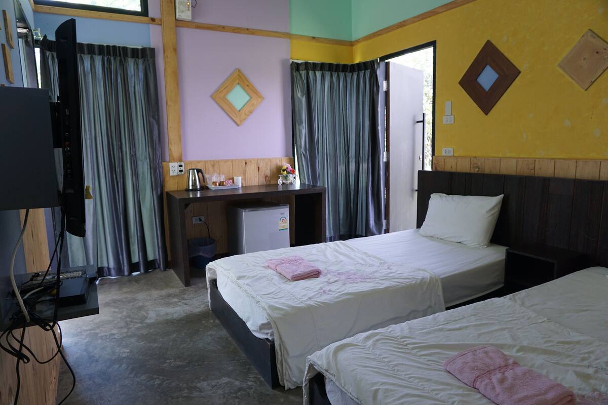 Una habitación de hotel con dos camas, un escritorio, un televisor y cortinas.
