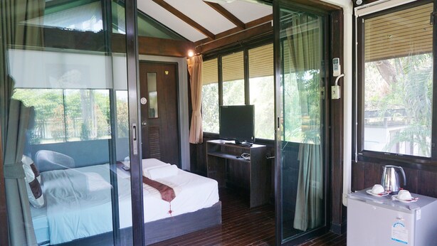 A bedroom with a bed, a desk with a computer, and a small refrigerator. - The Lampang Villa (Lampang)