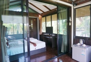 A bedroom with a bed, a desk with a computer, and a small refrigerator. - The Lampang Villa (Lampang)