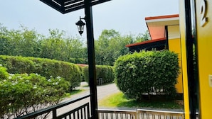 A covered outdoor area with a pathway, a lamp post, and a yellow building. - Kanyaphat Gardenview Resort (Ban Dung)
