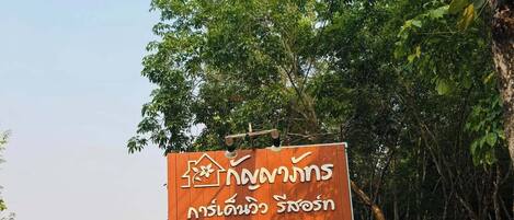 A sign for Kanyaphat Garden View Resort with Thai text and a contact number.
