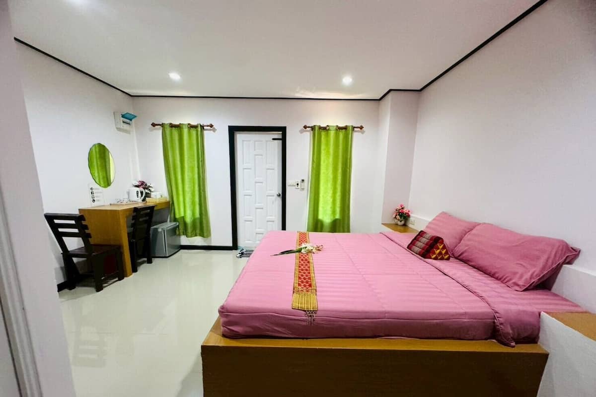 A bedroom with a bed, a desk, and a chair.