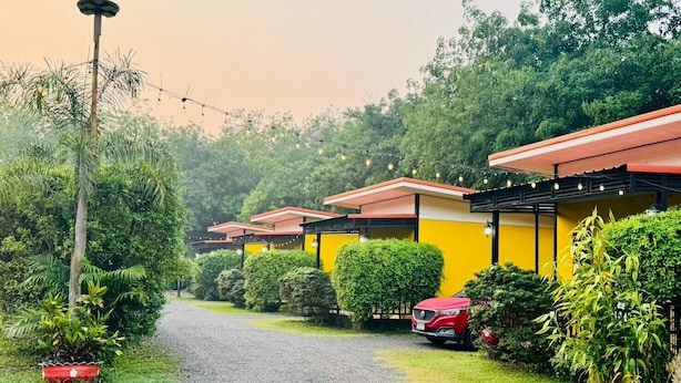 A row of yellow and red-roofed cabins with a gravel path leading through a green landscape. - Kanyaphat Gardenview Resort (Ban Dung)