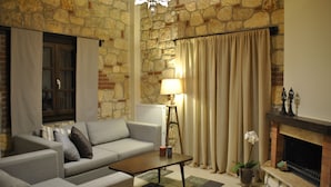A living room with a stone wall, a fireplace, a sofa, a coffee table, and a lamp.