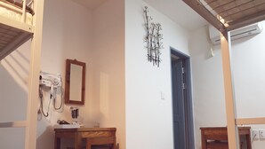 A room with a wooden table, chairs, a mirror, a wall-mounted heater, and a door. - Hostel Foryou (Yeosu)