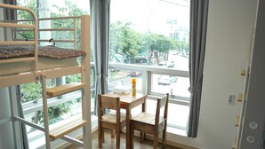 A bunk bed with a wooden table and chairs in a room with a large window. - Hostel Foryou (Yeosu)