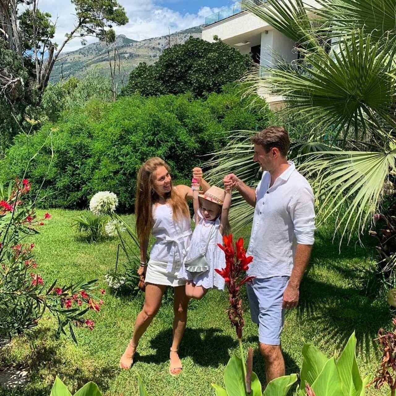 A family in a lush garden with a modern house in the background.