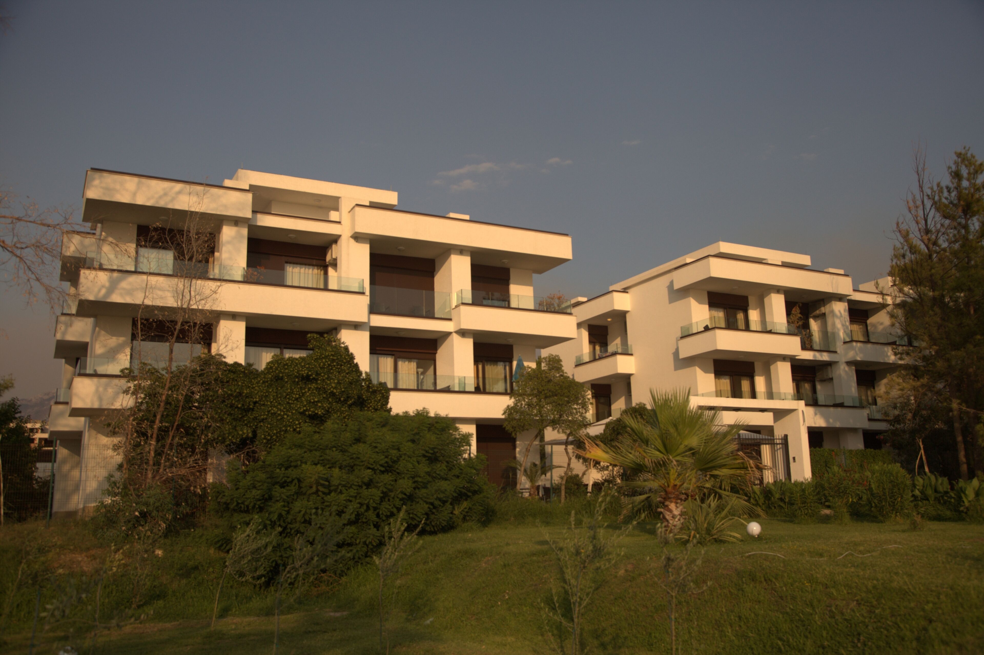 Un moderno edificio residenziale a più piani con balconi, immerso nel verde.