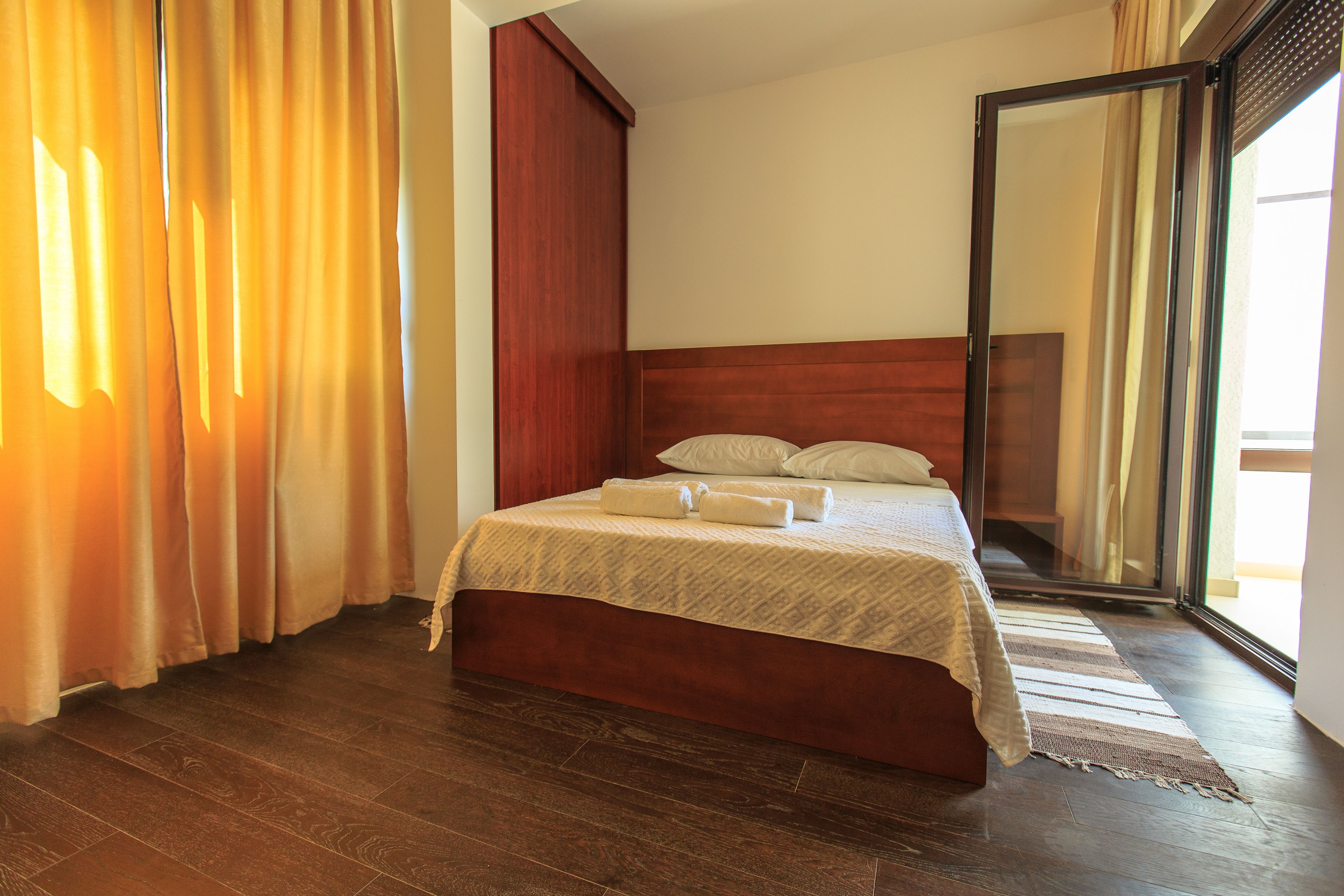 Una habitación de hotel con una cama de madera, un espejo grande y vistas a través de una puerta corredera.