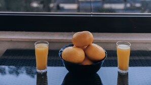 A table with a bowl of oranges and two glasses of orange juice, with a view of the sunset over the ocean. - Apartments Kuce Lekovica snack bar- Bistro & Beach  (Bar)