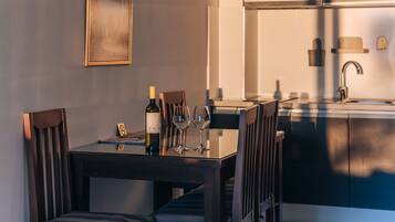 Un comedor con una mesa dispuesta para seis personas, una botella de vino y copas. Hay un cuadro en la pared y una lámpara colgante sobre la mesa.