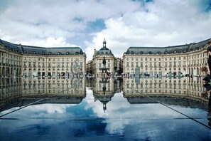 A symmetrical building with a central dome and a reflection in a water surface. - Enight (Gradignan)