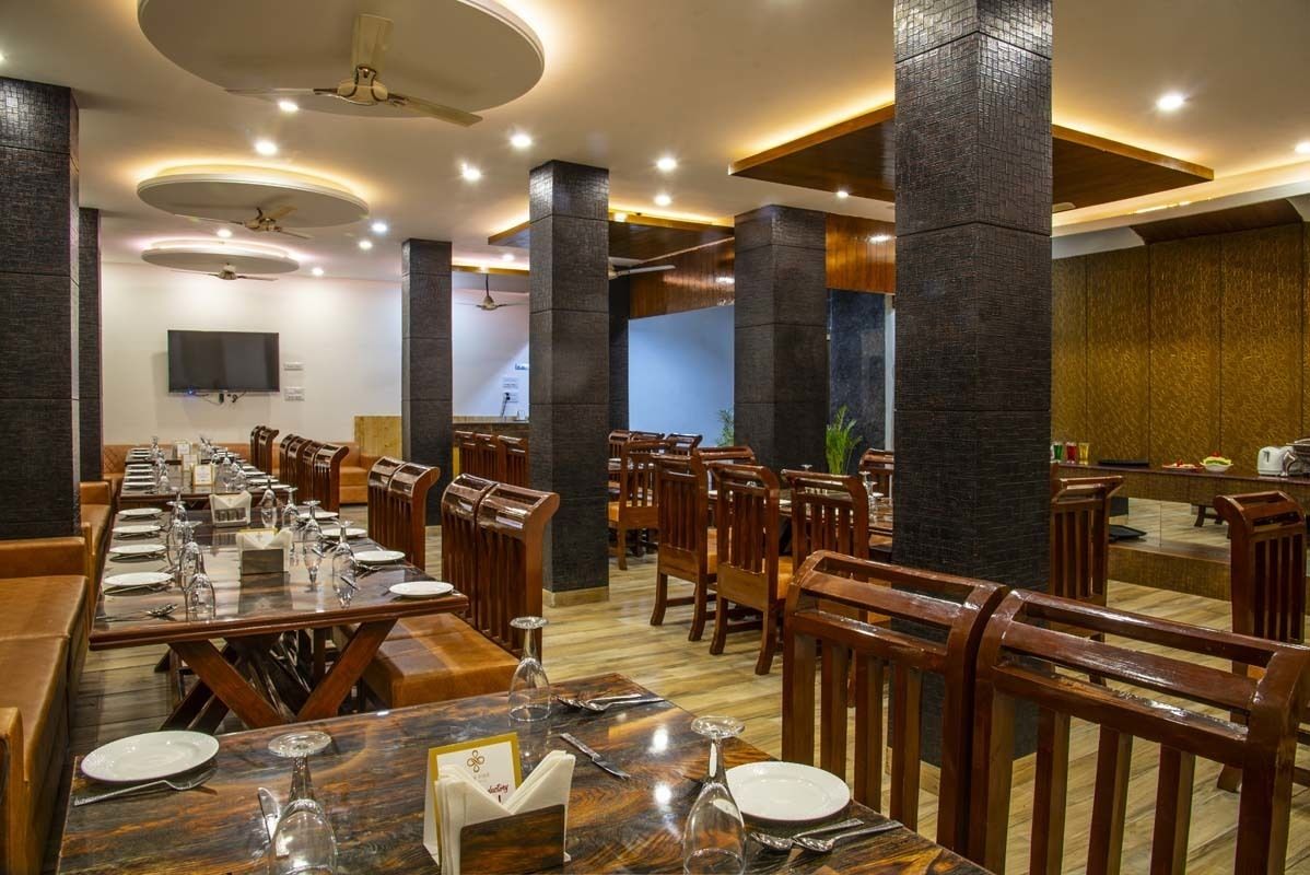 A restaurant with wooden tables and chairs, a TV mounted on the wall, and a ceiling fan.