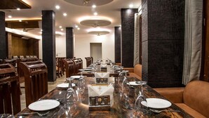 A dining area with a long wooden table set for a meal, surrounded by wooden chairs. - Jade Vine Resort (Shimla)