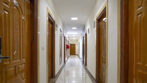 A long, narrow hallway with wooden doors on both sides, leading to a room at the end. - Jade Vine Resort (Shimla)