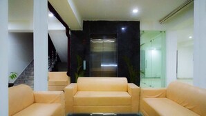 A lobby with a staircase, a glass elevator, and two beige sofas. - Jade Vine Resort (Shimla)