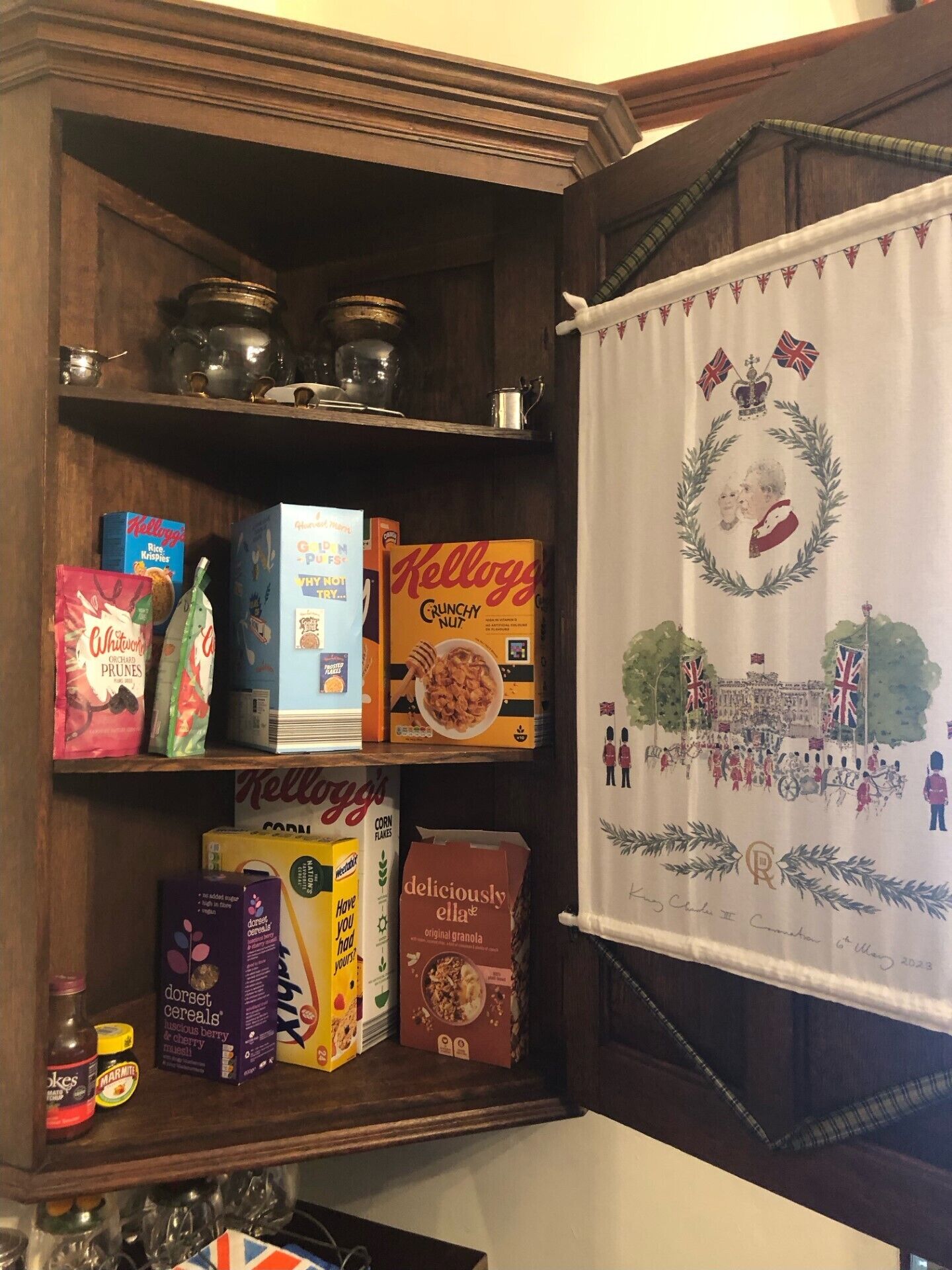 A shelf with various cereal boxes and jars.