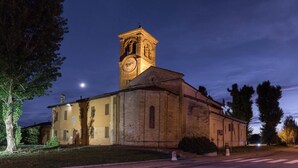 Une église dotée d’un clocher abritant une horloge, d’un beffroi et d’une croix au sommet.