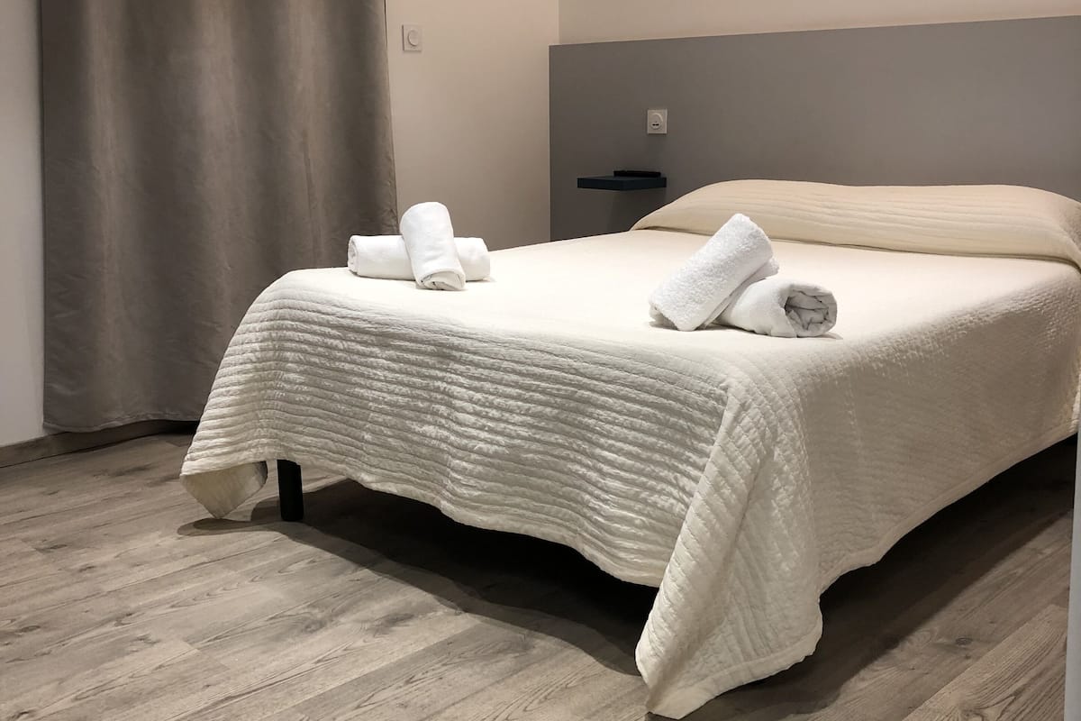 Quarto moderno com uma cama grande, cabeceira e piso de madeira.
