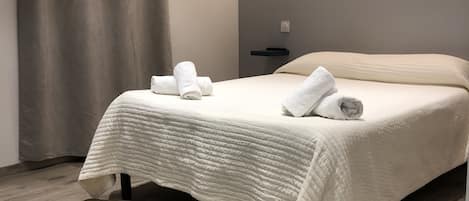Un dormitorio moderno con una cama grande, cabecera y suelo de madera.