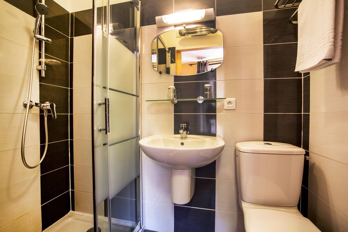 Um banheiro moderno com box de vidro, pia branca e vaso sanitário.