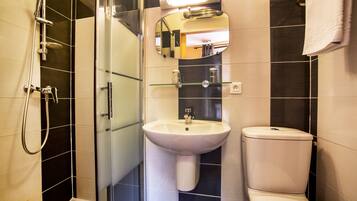 Une salle de bain moderne avec une douche à parois de verre, un lavabo blanc et des toilettes.