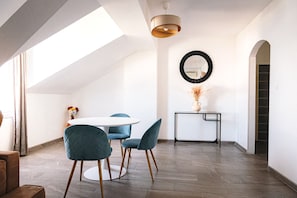 Un interior moderno con una mesa de comedor redonda, sillas tapizadas en azul, un mueble consola negro con un jarrón y un espejo grande en la pared.