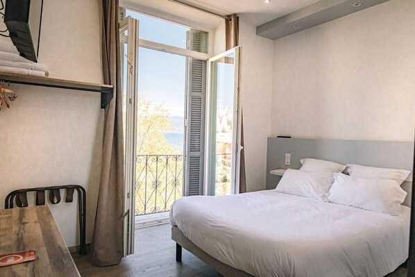 Habitación de hotel con cama, escritorio y balcón con vistas.