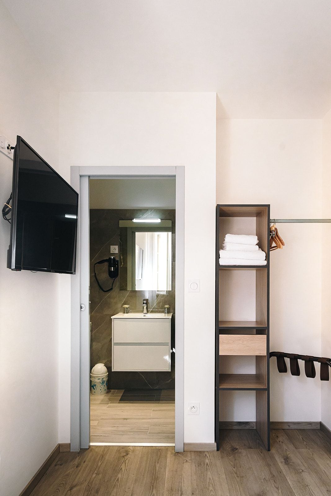 Un baño moderno con tocador, espejo y zona de ducha.