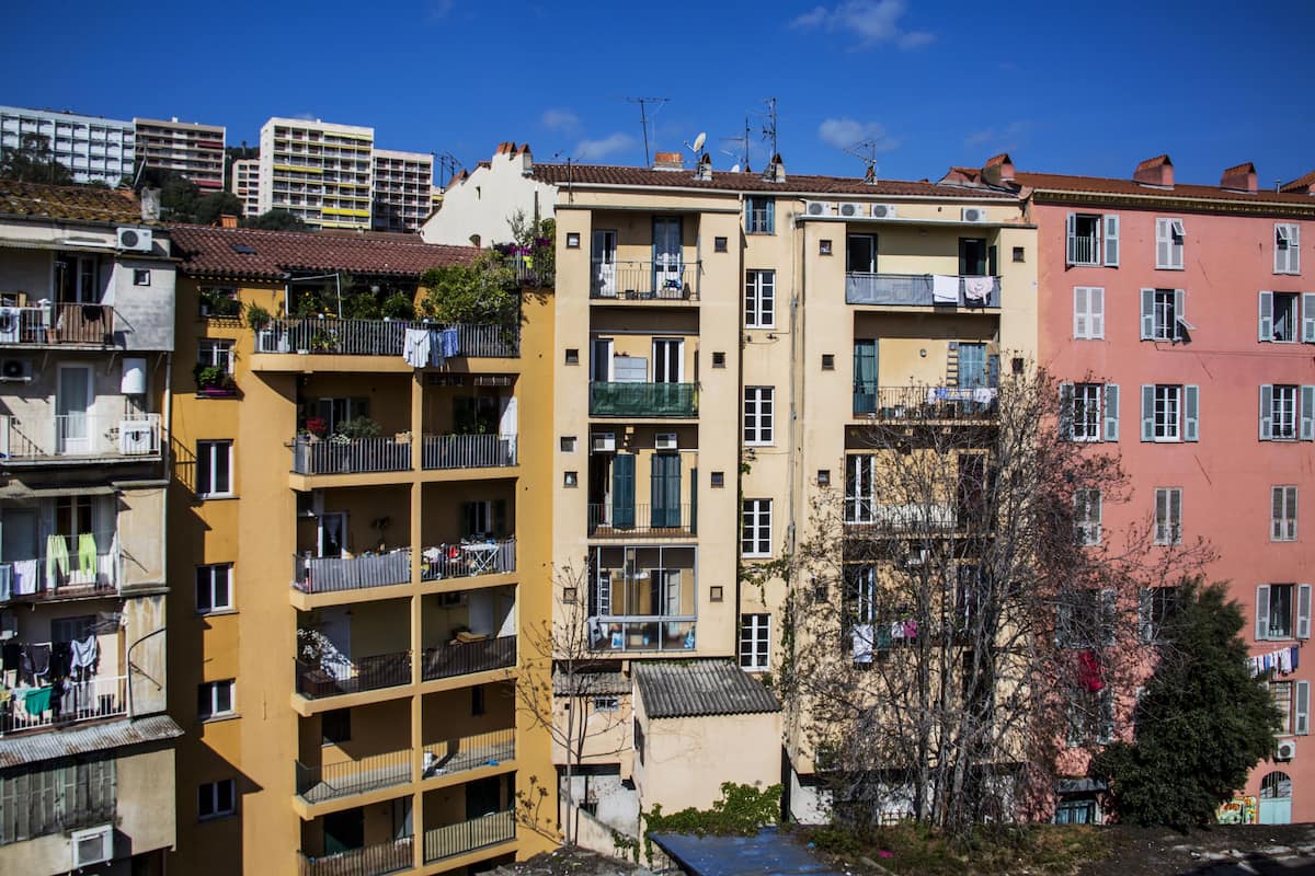 Edifício residencial com vários andares, varandas, aparelhos de ar condicionado e roupas penduradas no varal.