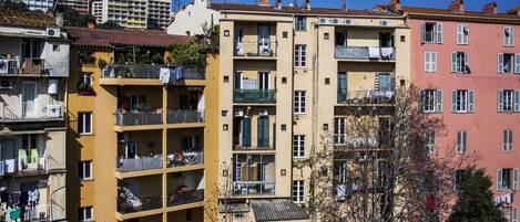 Un edificio residencial de varios pisos con balcones, aires acondicionados y ropa tendida.