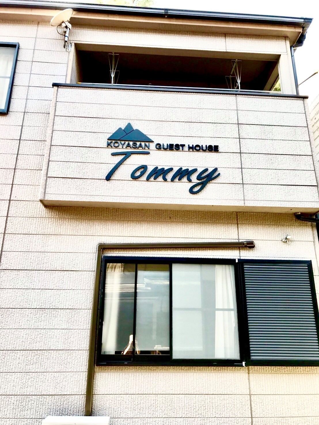 A building with a sign that reads "Koyasan Guest House Tommy".