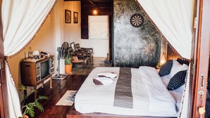 A cozy room with a bed, a television, a fan, and a dartboard on the wall. - Taloh Homestay Chiangmai (Mae On)
